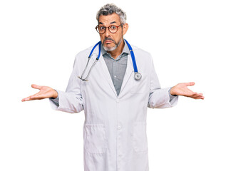 Middle age grey-haired man wearing doctor uniform and stethoscope clueless and confused expression...