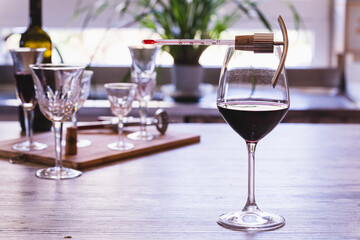A wine thermometer on a glass of red wine, with elegant glasses of wine in the background