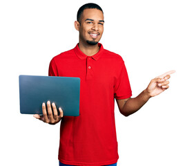Young african american man working using computer laptop smiling happy pointing with hand and...