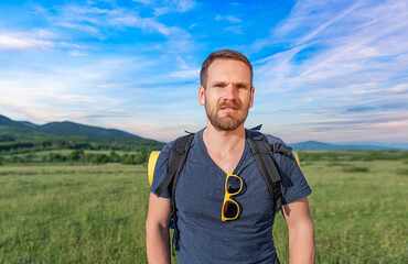 Young male traveler with a backpack in a natural landscape.