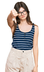 Young beautiful caucasian girl wearing casual clothes and glasses looking unhappy and angry showing rejection and negative with thumbs down gesture. bad expression.