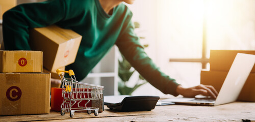 Startup SME small business entrepreneur of freelance Asian woman wearing apron using laptop and box...