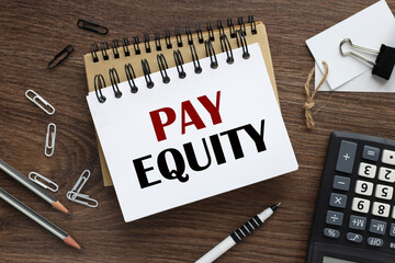 pay equity. two notepads and a calculator. text on white paper