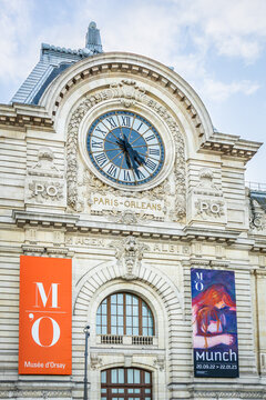 Munch exhibition poster and facade of the Orsay museum with view on the giant clock in Paris, France