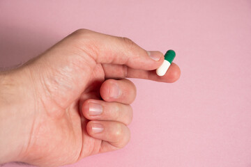 Mano sosteniendo píldora de color blanco y verde - Hand holding white and green pill