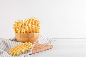 Ferratelle or pizzelle a traditional dessert or cookies in a bowl on a white wooden background, copy space. Regional cuisine of Abruzzo, Italy. Like the well-known waffle