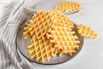 Ferratelle or pizzelle a traditional dessert or cookies on a plate on a white wooden background, close up. Regional cuisine of Abruzzo, Italy. Like the well-known waffle