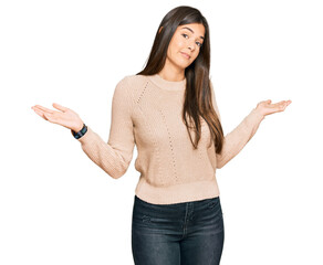 Young brunette woman wearing casual winter sweater clueless and confused expression with arms and...
