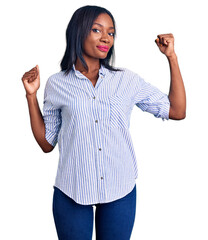 Obraz premium Young african american woman wearing casual clothes showing arms muscles smiling proud. fitness concept.
