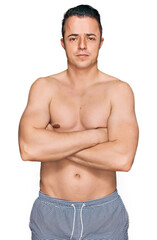 Fototapeta premium Handsome young man wearing swimwear shirtless skeptic and nervous, disapproving expression on face with crossed arms. negative person.