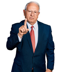Senior man with grey hair wearing business suit and glasses pointing with finger up and angry...