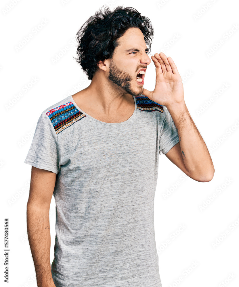 Wall mural Young hispanic man wearing casual t shirt shouting and screaming loud to side with hand on mouth. communication concept.