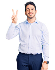 Young hispanic man wearing business clothes showing and pointing up with fingers number two while smiling confident and happy.
