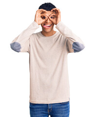 Fototapeta premium Young african amercian man wearing casual clothes doing ok gesture like binoculars sticking tongue out, eyes looking through fingers. crazy expression.