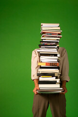 man carrying a stack of books isolated on green background, stacked books, space for text
