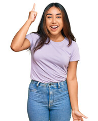 Young latin woman wearing casual clothes pointing finger up with successful idea. exited and happy. number one.