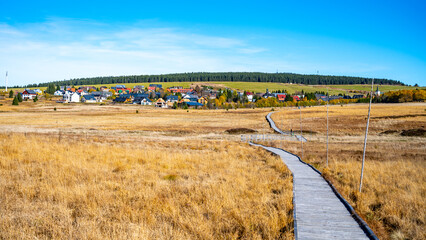 Wooden path in Bozi Dar peat bog nature reservation on sunny autumn day. Ore Mountains, Czech: Krusne hory, Czech Republic