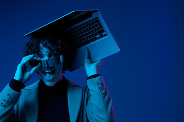 Portrait of stylish man hacker with laptop and futuristic glasses in blue light, cyber security, technology and education