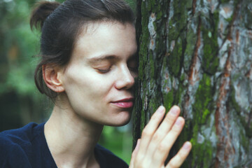 Young woman touching tree trunk, spiritual healing, love nature