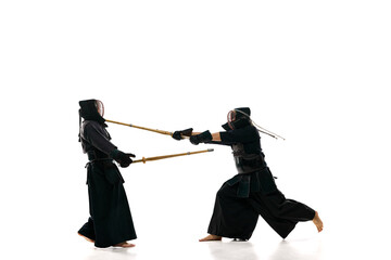 Men, professional kendo athletes in uniform raining with shinai sword against white studio background. Winner. Concept of martial arts, sport, Japanese culture, action and motion, strength