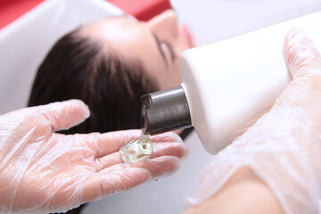 Shampoo in the hands of a master. A close-up hair wash.A woman washes her hair in a beauty salon. Out of focus. The concept of a beauty salon.
