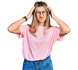 Obraz na płótnie Canvas Hispanic young woman wearing casual t shirt and glasses suffering from headache desperate and stressed because pain and migraine. hands on head.