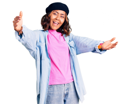 Young beautiful mixed race woman wearing french look with beret looking at the camera smiling with open arms for hug. cheerful expression embracing happiness.
