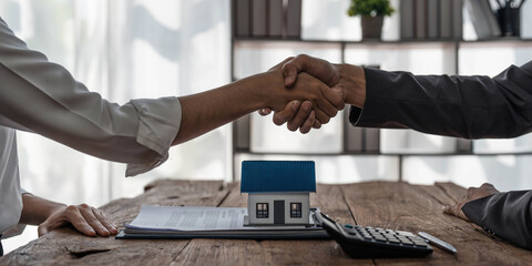 Real estate agent or realtor shakes hands with her client after making the deal in the office. cropped shot - obrazy, fototapety, plakaty