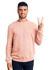 Naklejka premium Young hispanic man wearing casual clothes showing and pointing up with fingers number two while smiling confident and happy.