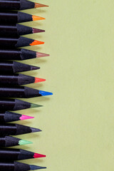 Lapis preto com pontas coloridas e fundo amarelo