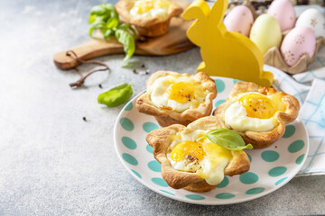Easter breakfast idea. Scrambled eggs in puff pastry with cheese and bacon on a stone background. Copy space.