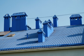 Blue roof of house with tiles and ventilation tubing