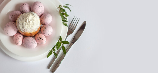 Homemade Easter bread and painted Easter eggs with spring flowers on a white plate on the table. Easter. Cutlery. Copy space banner