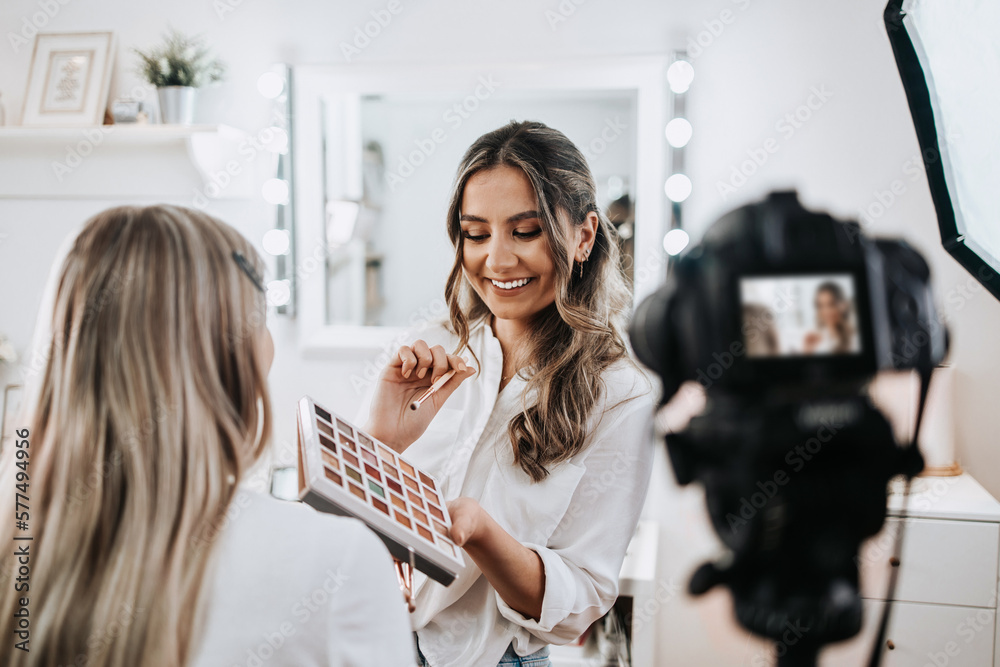 Wall mural happy young woman streaming a beauty makeup vlog from home or workshop. beautiful online content cre