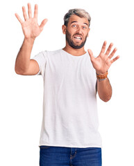 Fototapeta premium Young handsome blond man wearing casual t-shirt smiling with hands on chest with closed eyes and grateful gesture on face. health concept.