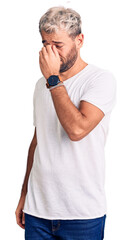 Young handsome blond man wearing casual t-shirt tired rubbing nose and eyes feeling fatigue and headache. stress and frustration concept.