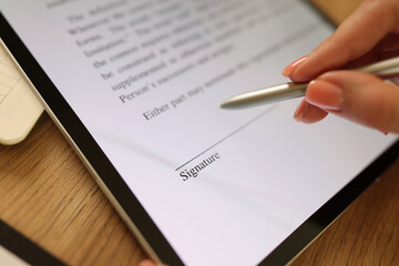 Female hand signing e-document with stylus on tablet