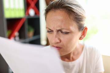 Focused woman trying read papers, squinting to see more clearly