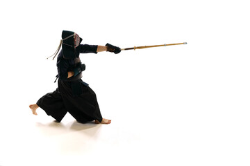 Man, professional kendo athlete in uniform with helmet training with bamboo shinai sword against white studio background. Concept of martial arts, sport, Japanese culture, action and motion