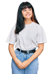 Young hispanic girl wearing casual clothes looking away to side with smile on face, natural expression. laughing confident.