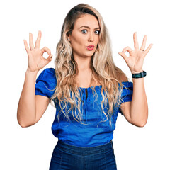 Fototapeta premium Young blonde woman wearing casual clothes looking surprised and shocked doing ok approval symbol with fingers. crazy expression