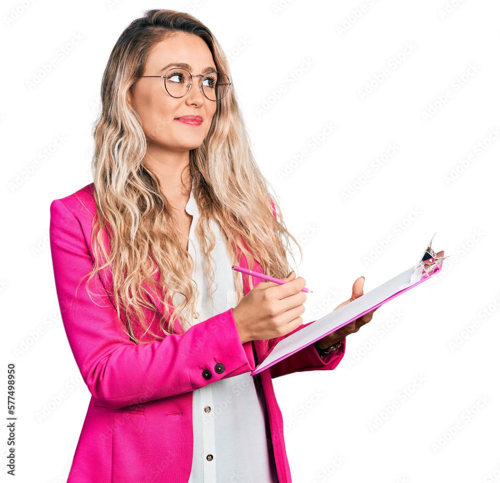 Sticker young blonde woman writing on clipboard smiling looking to the side and staring away thinking.