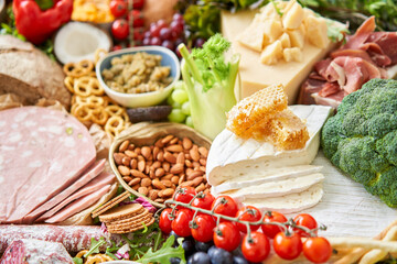 Brie cheese with honey close-up. Table full of mediterranean appetizers, tapas or antipasto. Assorted Italian food set. Delicious snack on party or picnic time. Italian style banquet. 