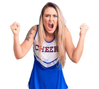 Young beautiful blonde woman wearing cheerleader uniform angry and mad raising fists frustrated and furious while shouting with anger. rage and aggressive concept.