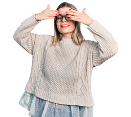 Young blonde woman wearing glasses covering eyes with hands smiling cheerful and funny. blind concept.