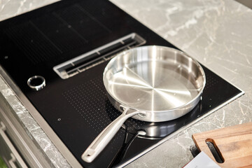 New cookware set on black induction hob in modern kitchen. Pot and frying pan in the kitchen on the...