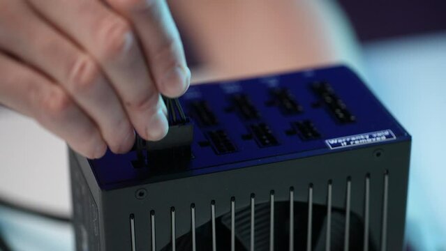 Extreme close-up of unrecognizable man connecting power supply to SSD by serial ata sata cable. Close up of stages of upgrading or assembling desktop computer. Shooting in slow motion.