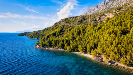 Take in the beauty of Croatia's coastal region from a new perspective with this stunning drone view, which features clear blue water and forested land.