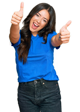 Beautiful brunette young woman wearing casual clothes approving doing positive gesture with hand, thumbs up smiling and happy for success. winner gesture.