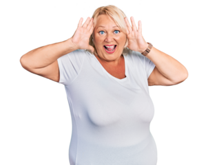 Middle age blonde woman wearing casual white t shirt smiling cheerful playing peek a boo with hands showing face. surprised and exited